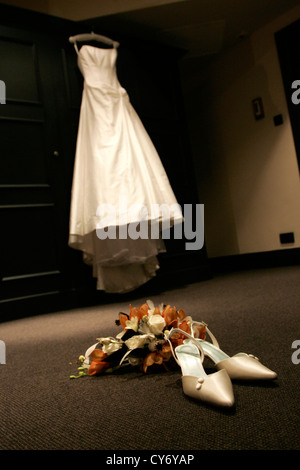 Braut Brautkleid hängen, Kleiderschrank mit Schuhen und Strauß im Vordergrund, Detail-Schuss Stockfoto