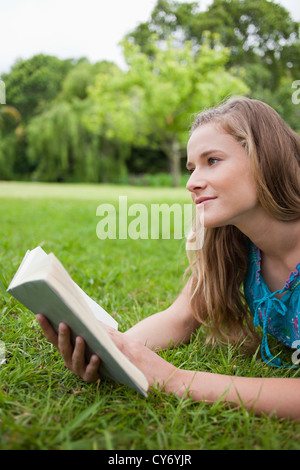 Nachdenkliche junge Frau hält ein Buch beim wegsehen Stockfoto