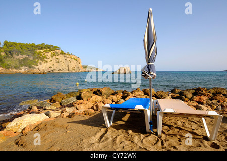 Zwei Stühle und ein Regenschirm an einem Strand in Ibiza, Spanien. Stockfoto