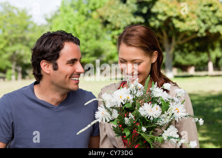 Frau, die gerne in einem Haufen Blumen suchen, wie sie von ihrem Freund beobachtet wird Stockfoto