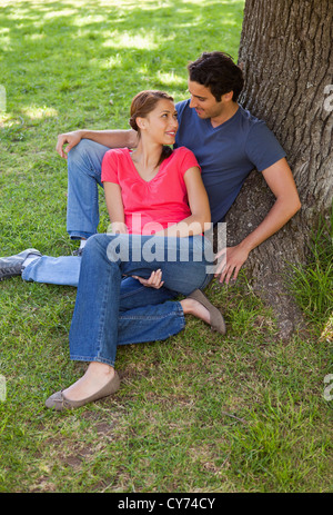 Zwei Freunde sahen einander während der Sitzung gemeinsam gegen einen Baum Stockfoto