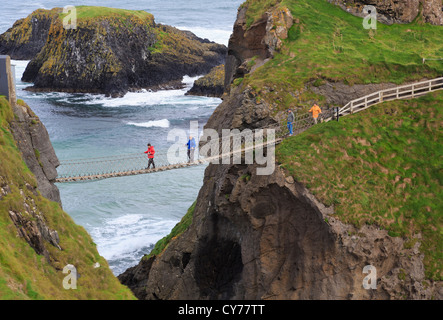 Menschen zu Fuß auf Carrick-a-Rede Rope Bridge von Carrick Island mit dem Festland in County Antrim, Nordirland, Vereinigtes Königreich Stockfoto