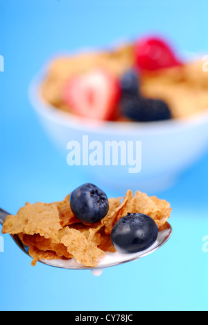 Löffel von knusprigen Bran Flakes mit Früchten mit Schüssel Müsli im Hintergrund Stockfoto