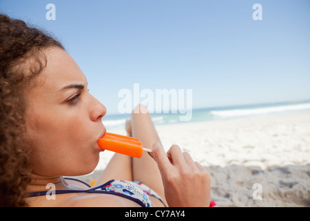 Junge attraktive Frau Essen ein Eis am Stiel am Strand Stockfoto