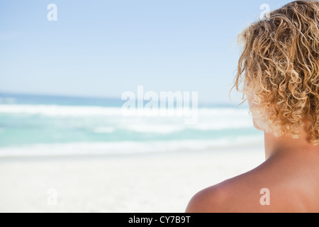 Junge blonde Mann beim Sonnenbaden mit Blick auf das Meer Stockfoto
