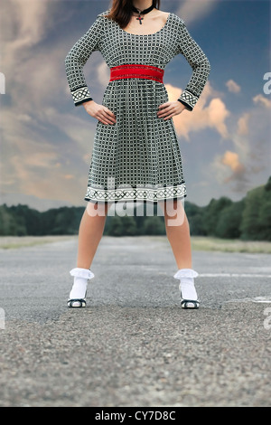 eine Frau in einem schwarzen und weißen Kleid steht auf einer Straße Stockfoto