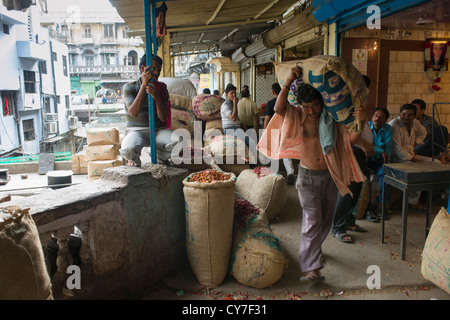 Porter tragen eine große Leinwand entlassen auf einer Veranda über eine Gasse von Khari Baoli Straße (Markt Gewürzbasar aus Chandni Chowk), Alt-Delhi, Indien Stockfoto