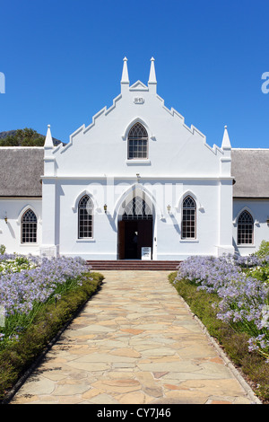 Weiße Kirche in Franschhoek vor blauem Himmel mit steinernen Weg Stockfoto