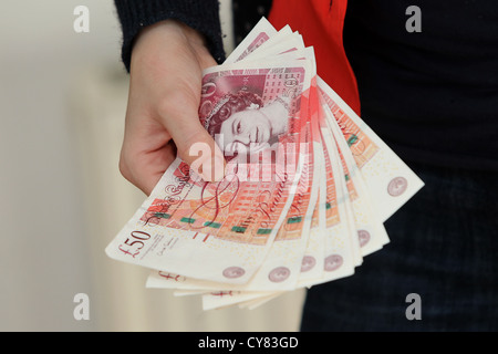 Ein junges Mädchen hält eine Reihe von fünfzig Pfund-Noten in Brighton, East Sussex, UK. Stockfoto