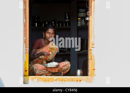 Junge indische Frau sitzt in ihrem Haus Tür Reis essen. Andhra Pradesh, Indien Stockfoto