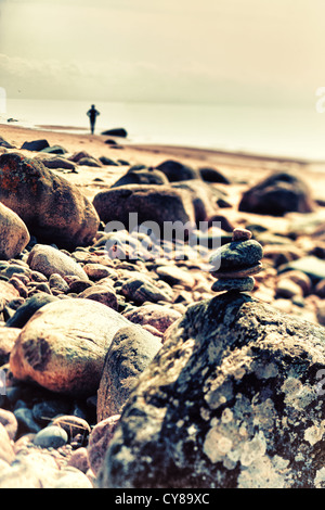 Rock Cairn und eine Silhouette an der felsigen Küste des Meeres. Ostsee. Kunst Stockfoto