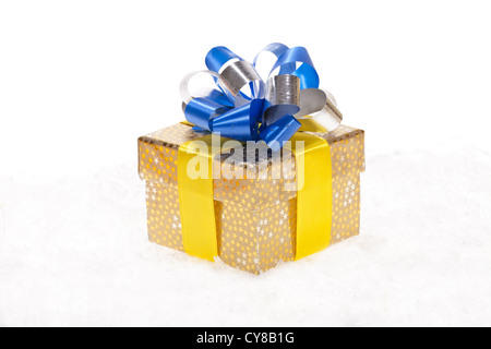 Goldene Weihnachtsgeschenk mit einem blauen und silbernen Farbe Band im Schnee isoliert auf weiss Stockfoto