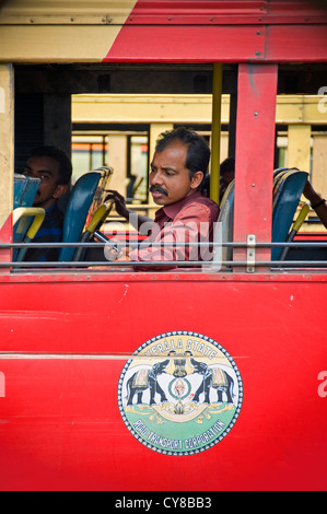 Vertikale Porträt eines Mannes sitzt auf einem klapprigen alten Bus mit einem Mobiltelefon in Kerala. Stockfoto