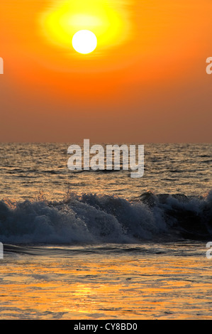 Vertikale Blick auf den Sonnenuntergang über den tosenden Wellen in Kerala, Indien. Stockfoto