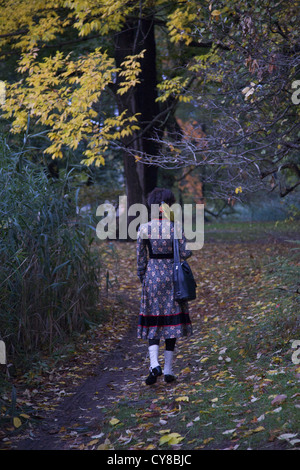 Junge Frau geht allein durch das Herbstlaub im Prospect Park, Brooklyn, NY. Stockfoto