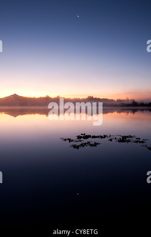 Sonnenaufgang im Nebel See Cassidy mit Mount Pilchuck Reflexionen und Halbmond Stockfoto