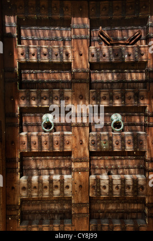 Balinesischen Stil großen geschnitzten Holztüren in Bali Indonesien mit Metall Türklopfer und Nieten. Stockfoto