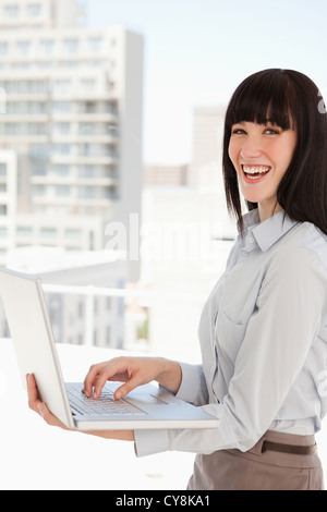 Lachende Geschäftsfrau mit einem Laptop in den Händen Stockfoto
