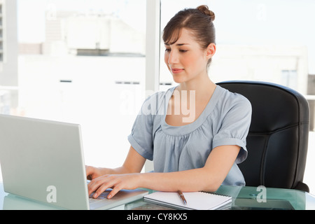 Brünette Mitarbeitertypen auf ihrem laptop Stockfoto