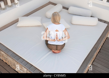 Frau tut reverse Gebet Pose auf Bett im Patio, Rückansicht Stockfoto