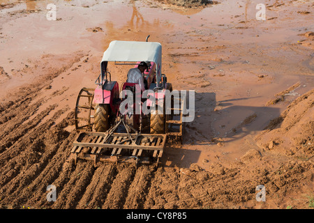 Pflügen Traktor vorbereiten ein Reisfeld Feld in der indischen Landschaft. Andhra Pradesh, Indien Stockfoto