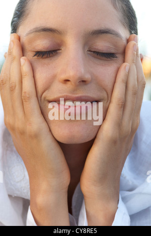 Junge Frau mit den Händen auf das Gesicht und die Augen geschlossen, Porträt Stockfoto
