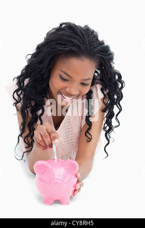 Ein junges Mädchen auf dem Boden, Geld in ein Sparschwein Stockfoto