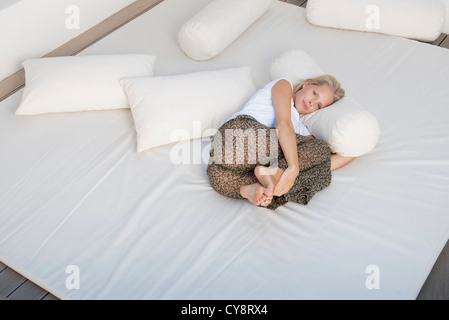 Junge Frau am Bett im fötalen Position entspannen Stockfoto