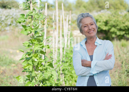 Ältere Frau lächelt stolz im Gemüsegarten Stockfoto