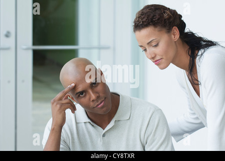 Junger Mann sitzen und Blick in die Kamera, junge Frau, die Neigung zu jungen Mann Stockfoto