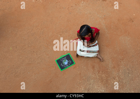 Indianerdorf Mädchen mit ONE WORLD geschrieben auf einer Tafel in einem indischen Dorf. Andhra Pradesh, Indien. Kopieren Sie Raum. Stockfoto