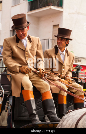 Wagen-Fahrer und Beifahrer in Top-Hats gekleidet und angebundene Mäntel in einer religiösen Prozession. Fuengirola. Spanien. Stockfoto