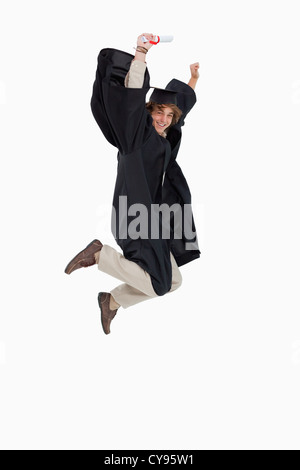 Glücklich männlichen Studenten im Diplom Gewand springen Stockfoto