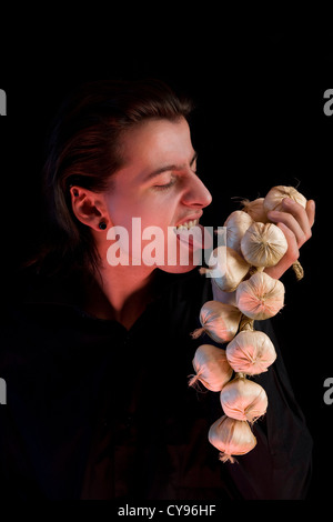 Vampir, lecken, Knoblauch, roten Horror Licht, isoliert auf schwarzem Hintergrund Stockfoto