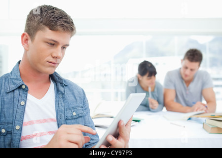 Ein Mann mit einem TabletPC arbeitet vor seinen Freunden Stockfoto