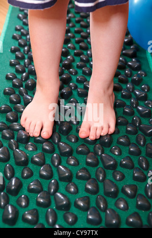 Kinder kleine Füße stehen auf massage Matte für Plattfuß Therapie Stockfoto