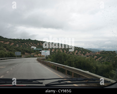 Einem regnerischen Tag fahren auf den Straßen in der andalusischen, Blick auf die Hügel von innerhalb einer Autostraße Olivenhaine und Scheibenwischer Stockfoto