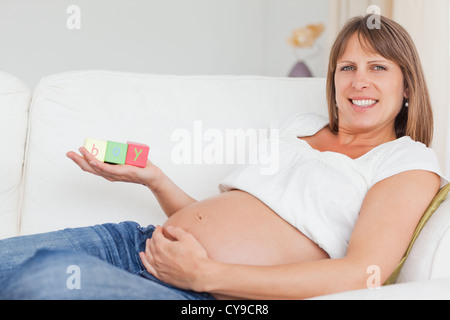 Schöne schwangere Frau mit Holzklötzen spielen und hat das Wort "junge" auf ihre Hand geschrieben Stockfoto