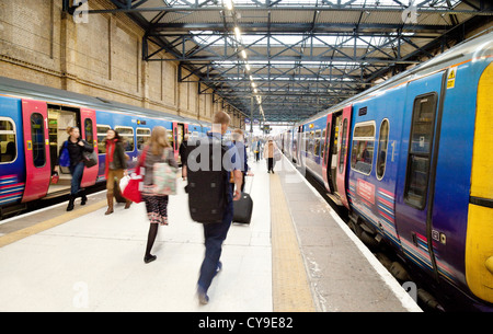 Menschen hetzen, um einen Zug auf dem Bahnsteig, Bahnhof Kings Cross, London UK Stockfoto