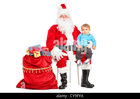 Ein Weihnachtsmann und kleines Kind auf seinem Schoß posiert neben einem Beutel voller Geschenke isoliert auf weißem Hintergrund Stockfoto