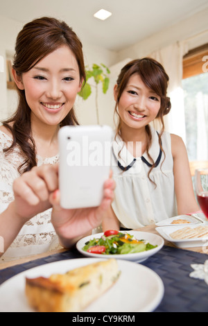 Zwei junge Frauen, die Aufnahme von Lebensmitteln mit Smartphone Stockfoto