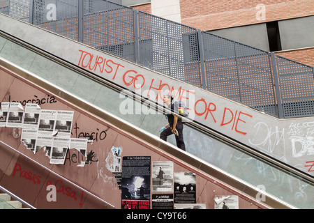 "Touristen gehen nach Hause oder sterben" an der Wand in der Nähe der Rolltreppe in Barcelona, Spanien. Konzept des Coronavirus...