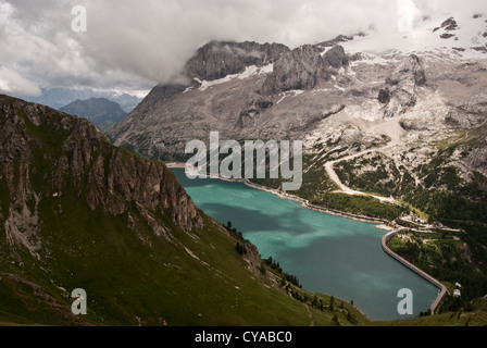 Lago di Fedaia Wasserbehälter mit Bergrücken der Marmolada mit Gletscher in den Dolomiten in Italien während Sommertag mit blauen Himmel und Wolken Stockfoto