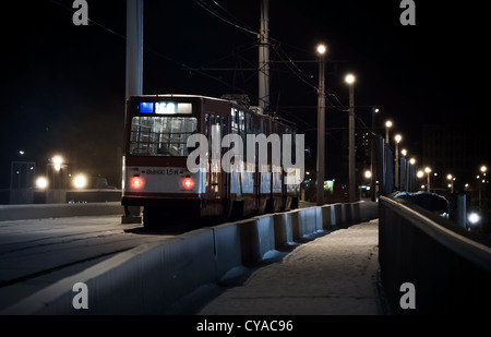 Die letzte Straßenbahn fährt über eine Brücke an einem Winterabend Stockfoto