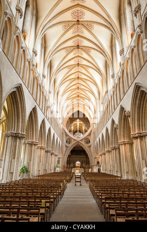 Mittelschiff der Kathedrale von Wells, Wells, Vereinigtes Königreich | WELLS, Vereinigtes Königreich — Das Mittelschiff der Kathedrale von Wells in Wells, Somerset, erstreckt sich in Richtung des Chors und der berühmten Scherenbögen dahinter. Die mittelalterliche Kathedrale wurde hauptsächlich zwischen 1175 und 1490 im frühen englischen Gotikstil erbaut und gilt als eines der schönsten und vollständigsten Beispiele der gotischen Architektur in Großbritannien. Die Kathedrale von Wells dient als Sitz des Bischofs von Bath und Wells, und das Mittelschiff bleibt das Prozessionsherz dieses aktiven Gotteshauses. Stockfoto