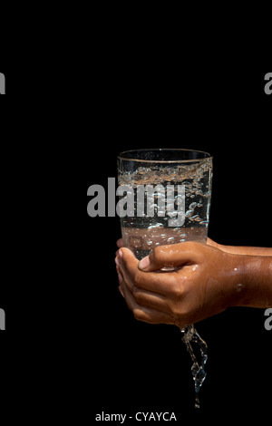 Sprudelnden Wasser in ein Glas von Inderinnen Händen gehalten Stockfoto