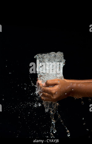 Sprudelnden Wasser in ein Glas von Inderinnen Händen gehalten Stockfoto