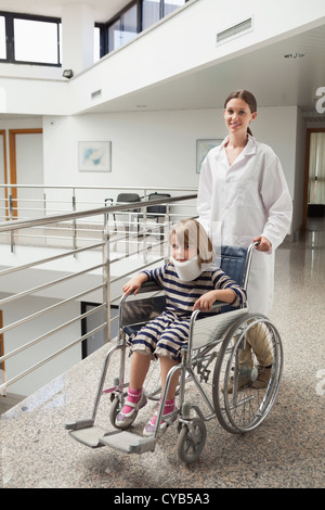 Kind in Halskrause von Arzt im Rollstuhl geschoben Stockfoto