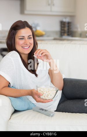 Frau Popcorn zu essen, während Sie gemütlich auf dem sofa Stockfoto