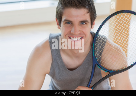 Glücklicher Mann hält einen Tennisschläger Stockfoto